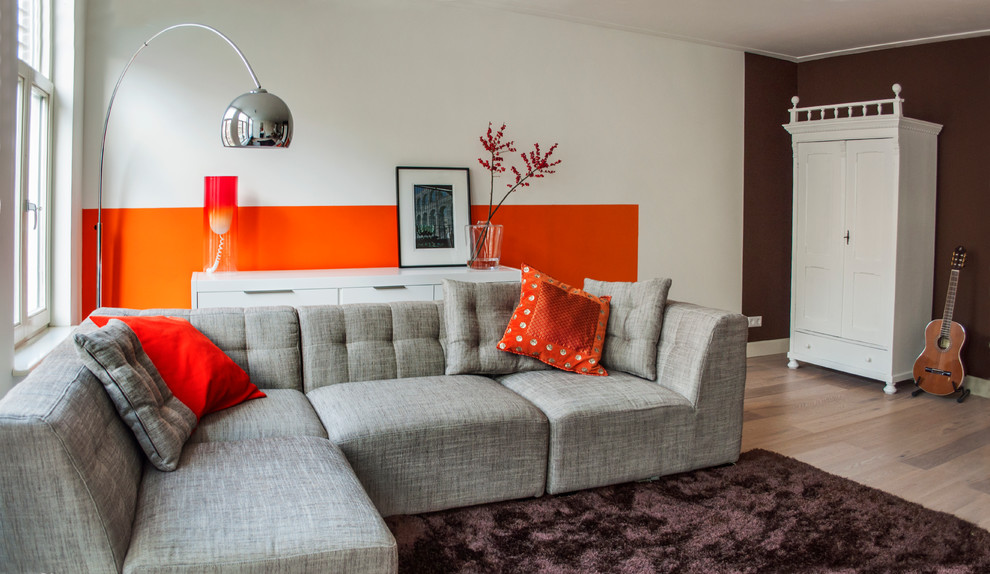 This is an example of a modern living room in Amsterdam with orange walls and beige floor.