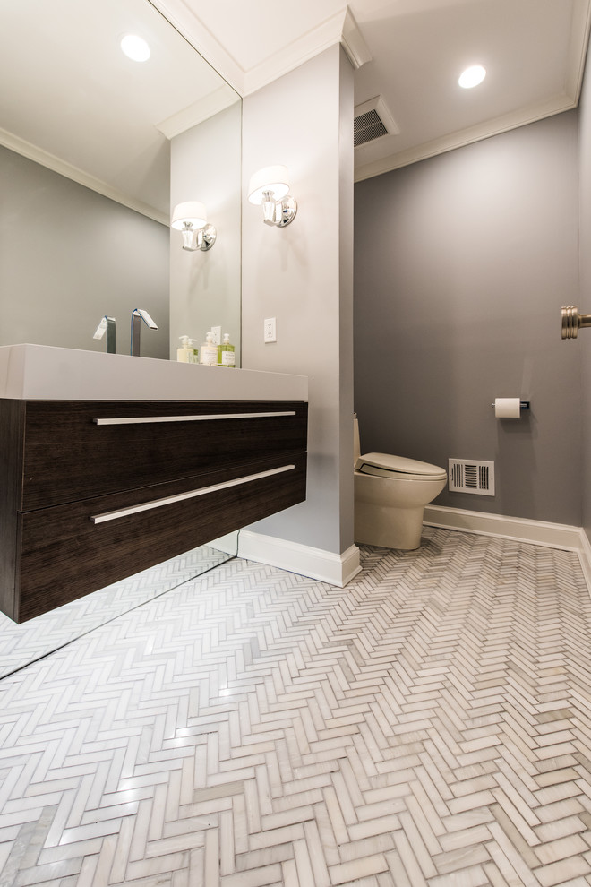 Inspiration for a mid-sized transitional 3/4 bathroom in DC Metro with flat-panel cabinets, dark wood cabinets, a one-piece toilet, gray tile, porcelain tile, blue walls, marble floors, solid surface benchtops and an integrated sink.