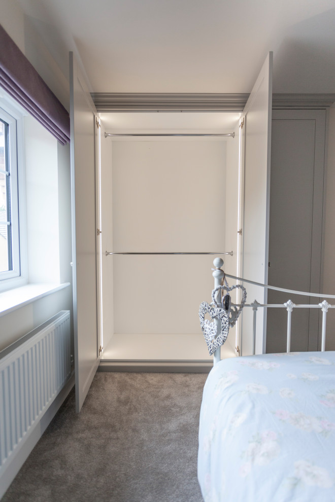 This is an example of a mid-sized modern gender-neutral storage and wardrobe in Cardiff with shaker cabinets, grey cabinets and carpet.