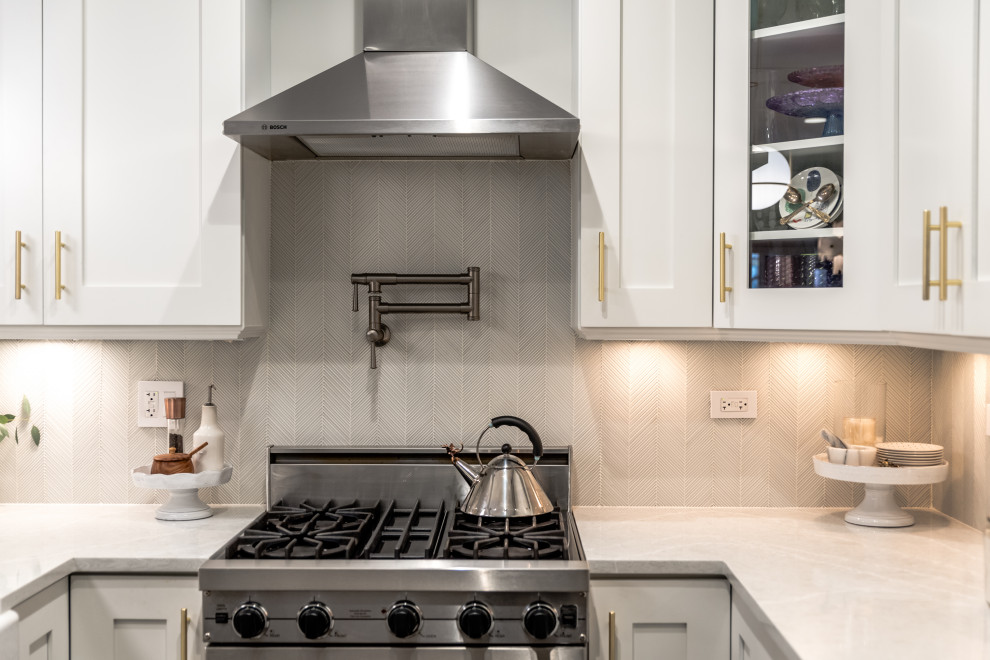 Example of a mid-sized transitional u-shaped dark wood floor and brown floor eat-in kitchen design in Chicago with a farmhouse sink, shaker cabinets, white cabinets, quartz countertops, gray backsplash, glass tile backsplash, stainless steel appliances, a peninsula and gray countertops