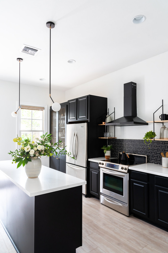 Transitional kitchen in New Orleans with raised-panel cabinets, black cabinets, black splashback, stainless steel appliances, light hardwood floors, with island, beige floor and white benchtop.