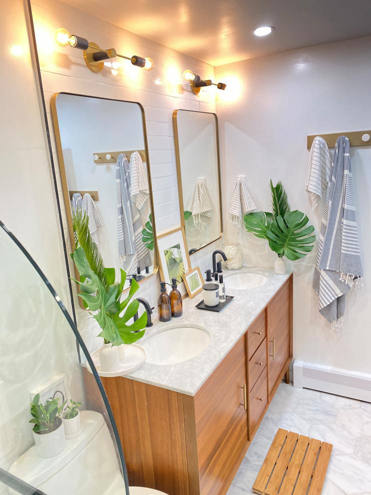 Photo of a mid-sized midcentury master bathroom in New York with flat-panel cabinets, medium wood cabinets, a drop-in tub, a one-piece toilet, gray tile, marble, white walls, an undermount sink, marble benchtops, grey benchtops, a double vanity and a freestanding vanity.