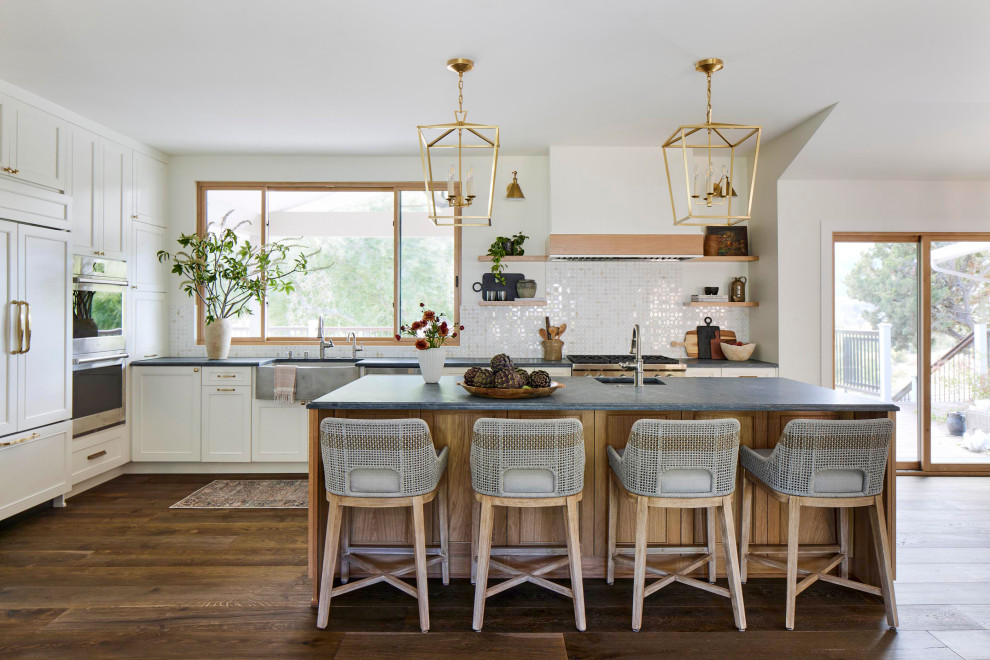 Large country l-shaped eat-in kitchen in San Francisco with a farmhouse sink, raised-panel cabinets, white cabinets, marble benchtops, multi-coloured splashback, marble splashback, panelled appliances, dark hardwood floors, with island and grey benchtop.