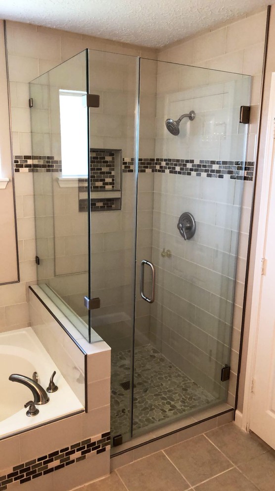 This is an example of a small contemporary bathroom in Houston with a drop-in tub, a corner shower, white tile, pebble tile floors, multi-coloured floor and a hinged shower door.