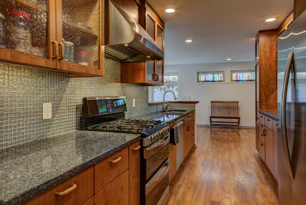 Inspiration for a transitional galley medium tone wood floor kitchen remodel in Hawaii with an undermount sink, flat-panel cabinets, medium tone wood cabinets, granite countertops, blue backsplash, glass tile backsplash, stainless steel appliances and no island