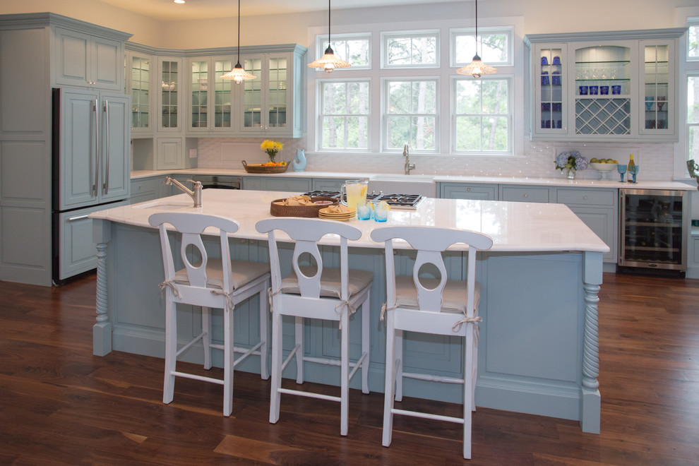 Inspiration for a large beach style l-shaped eat-in kitchen in Boston with white splashback, a farmhouse sink, beaded inset cabinets, blue cabinets, marble benchtops, panelled appliances, dark hardwood floors and with island.