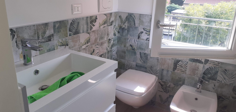 Cette photo montre un petit WC suspendu moderne avec un carrelage multicolore, des carreaux de porcelaine, un mur multicolore, sol en stratifié et un lavabo intégré.