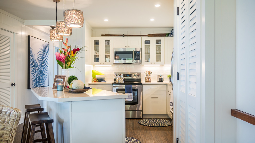 This is an example of a small beach style l-shaped open plan kitchen in Hawaii with an undermount sink, shaker cabinets, white cabinets, white splashback, subway tile splashback, stainless steel appliances, ceramic floors and with island.