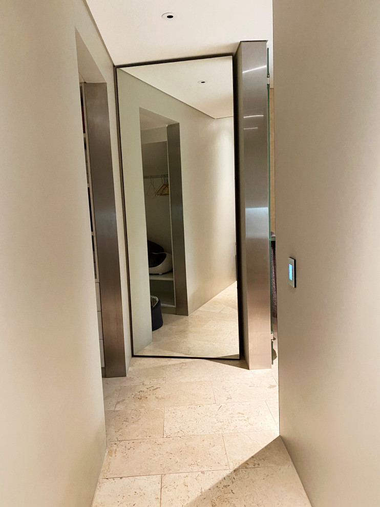 Photo of a mid-sized modern wet room bathroom in Sydney with a wall-mount toilet, beige tile, travertine, beige walls, travertine floors, an integrated sink, tile benchtops, a hinged shower door, an enclosed toilet, a single vanity, a built-in vanity and brick walls.
