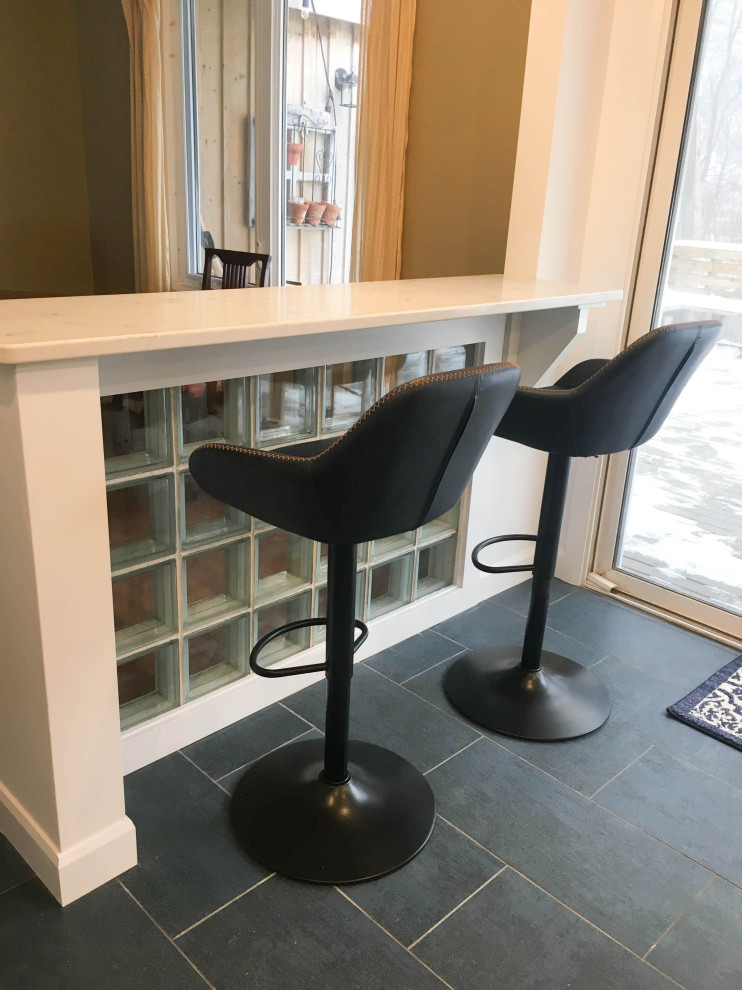 Example of a mid-sized transitional l-shaped porcelain tile and gray floor enclosed kitchen design with an undermount sink, shaker cabinets, white cabinets, granite countertops, gray backsplash, subway tile backsplash, stainless steel appliances, no island and white countertops