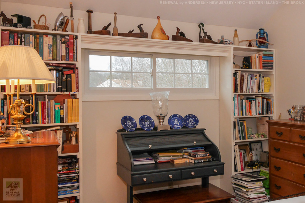 Bild på ett litet hemmabibliotek, med vita väggar, mörkt trägolv och ett fristående skrivbord
