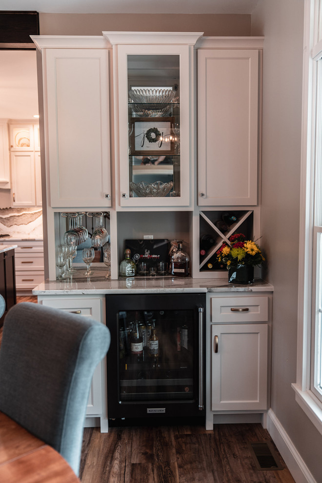 Example of a large transitional l-shaped medium tone wood floor and brown floor open concept kitchen design with an undermount sink, flat-panel cabinets, white cabinets, quartz countertops, multicolored backsplash, quartz backsplash, black appliances, an island and multicolored countertops