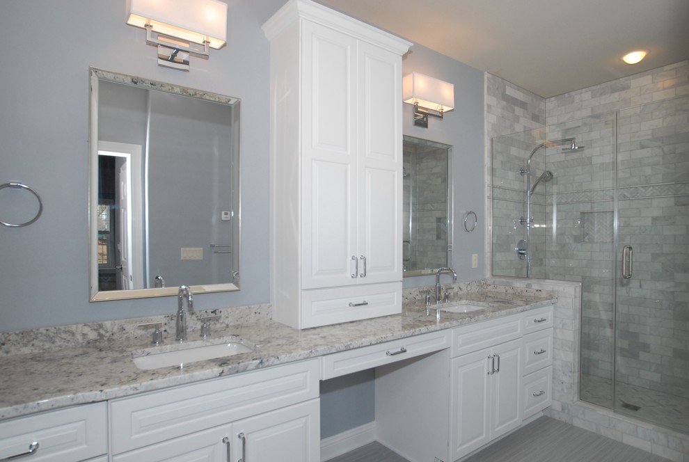 This is an example of a large traditional master bathroom in Milwaukee with an undermount sink, raised-panel cabinets, white cabinets, granite benchtops, a double shower, a two-piece toilet, gray tile, porcelain tile, grey walls, porcelain floors, grey floor and a hinged shower door.