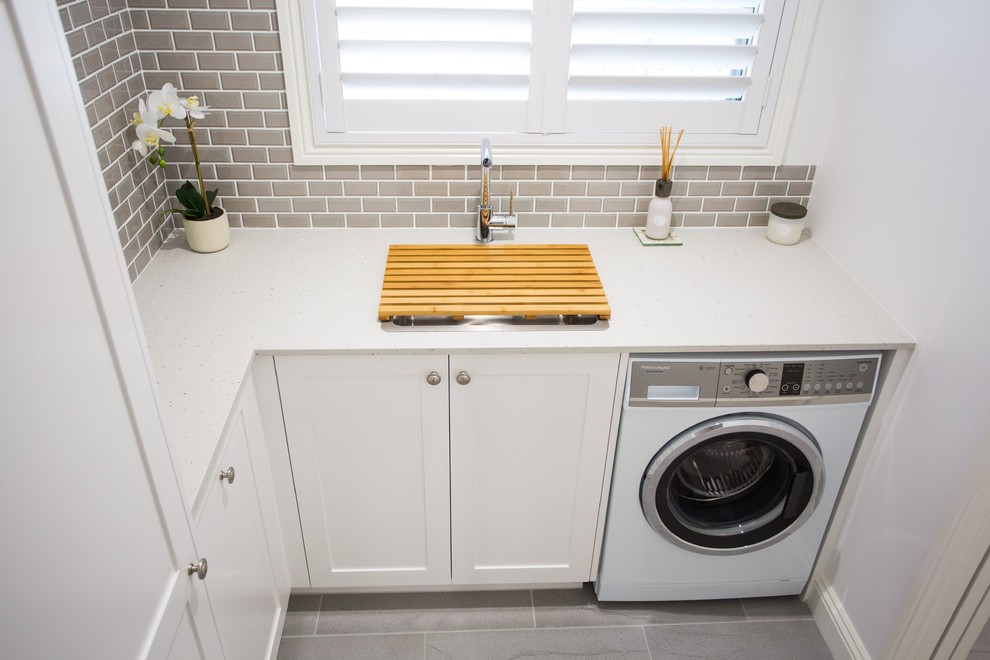 Inspiration for a small traditional l-shaped dedicated laundry room in Brisbane with a single-bowl sink, shaker cabinets, white cabinets, quartz benchtops, white walls, porcelain floors, grey floor and white benchtop.
