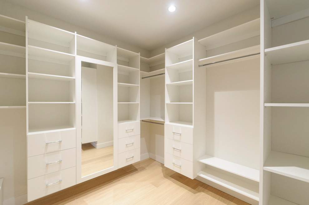 Inspiration for a large transitional walk-in wardrobe in Vancouver with open cabinets, white cabinets and light hardwood floors.
