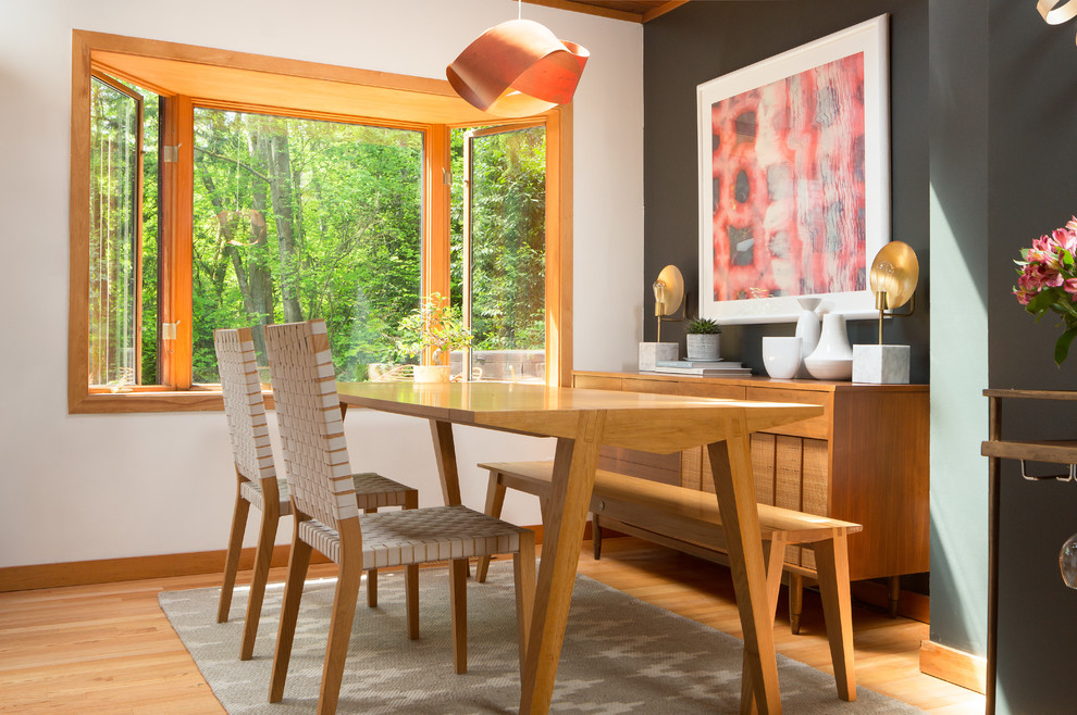 Photo of a midcentury dining room in Seattle with black walls and medium hardwood floors.