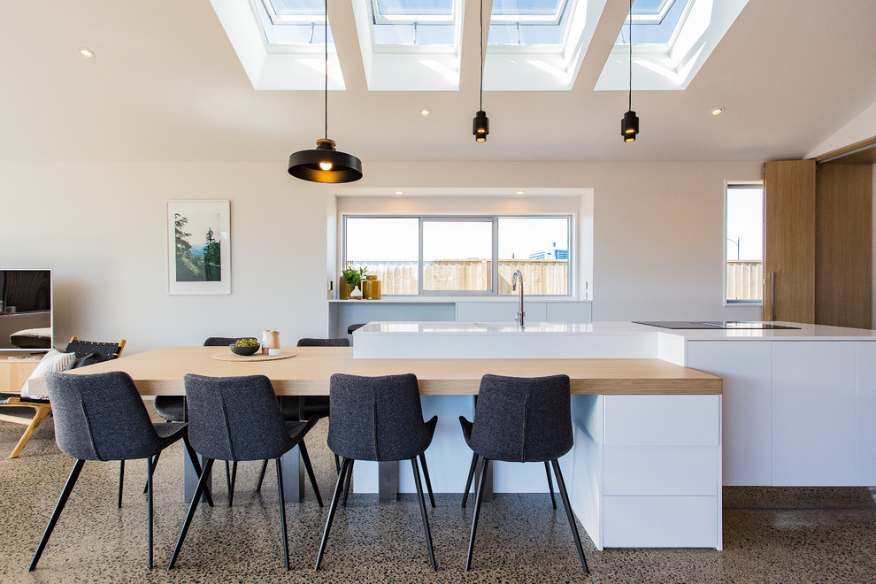Design ideas for a large modern single-wall eat-in kitchen in Christchurch with flat-panel cabinets, quartz benchtops, concrete floors, with island, a single-bowl sink, white cabinets, window splashback, stainless steel appliances, multi-coloured floor and white benchtop.