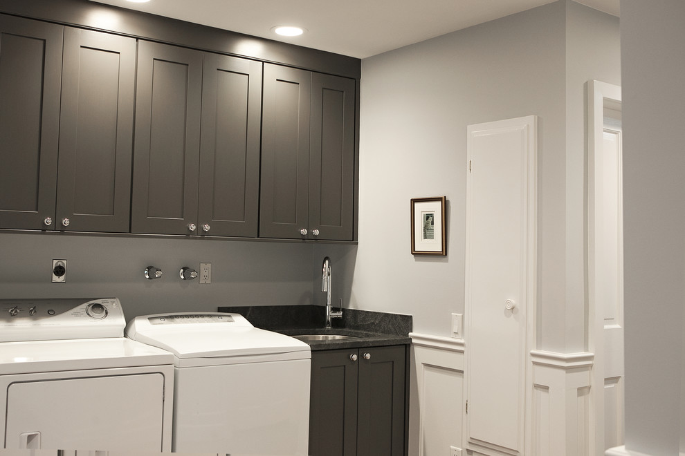 Traditional single-wall dedicated laundry room in New York with an undermount sink, shaker cabinets, grey cabinets, granite benchtops, grey walls and a side-by-side washer and dryer.