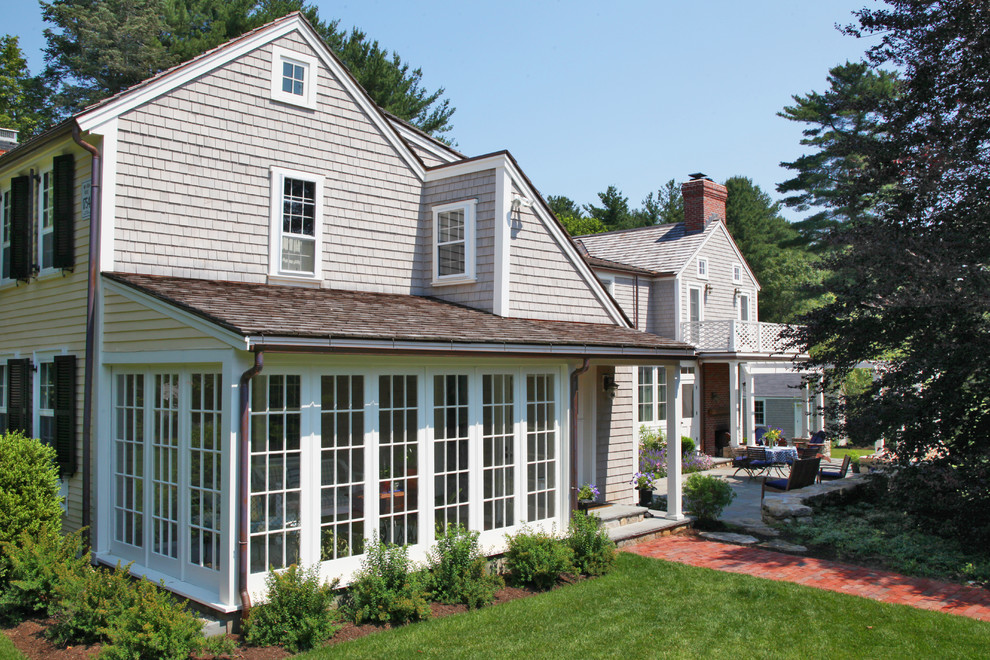 This is an example of a large traditional two-storey yellow house exterior in Boston with wood siding, a gable roof and a shingle roof.