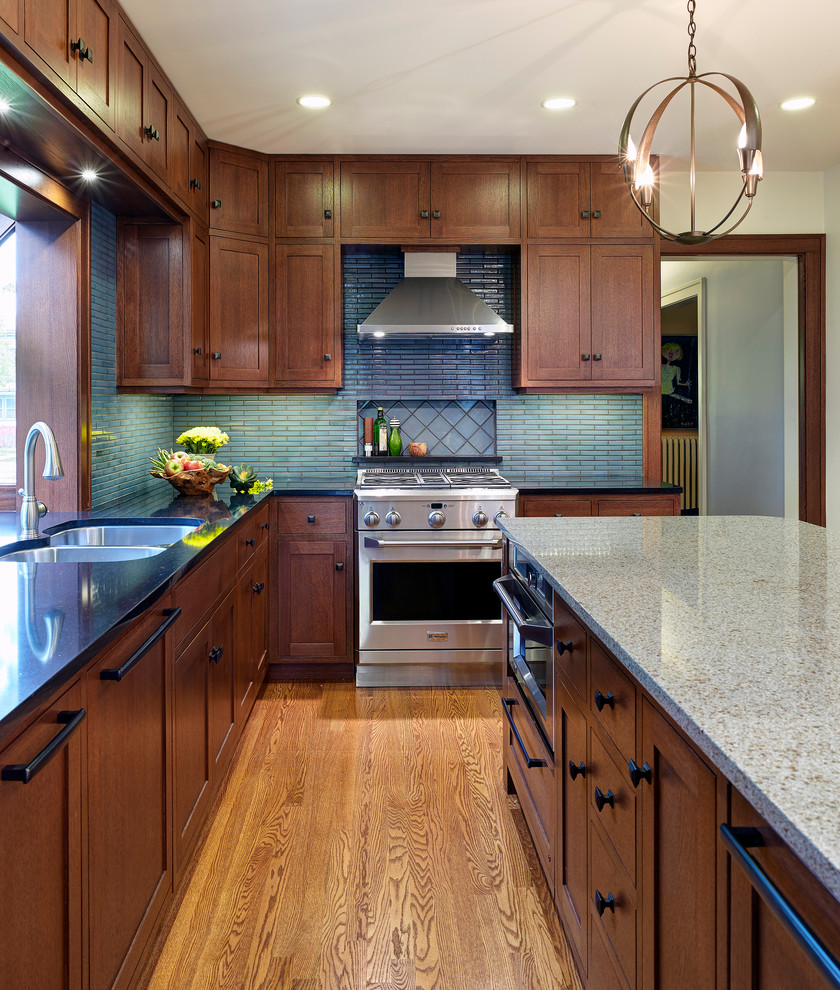 This is an example of a traditional kitchen in Chicago with a double-bowl sink, shaker cabinets, dark wood cabinets, blue splashback, stainless steel appliances, medium hardwood floors and with island.