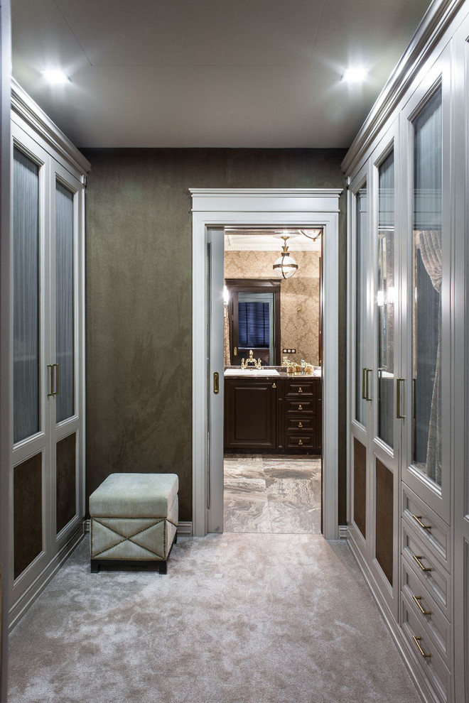 This is an example of a traditional gender-neutral dressing room in Moscow with carpet, recessed-panel cabinets and white cabinets.