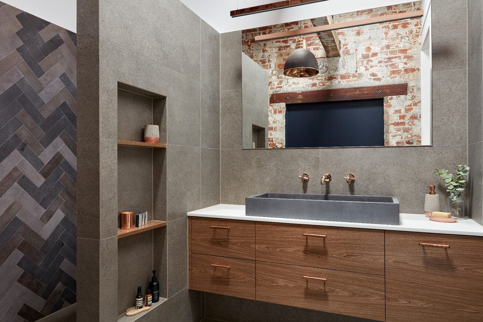 Photo of a large industrial master bathroom in Melbourne with flat-panel cabinets, dark wood cabinets, a freestanding tub, an alcove shower, a one-piece toilet, gray tile, porcelain tile, white walls, porcelain floors, a vessel sink, engineered quartz benchtops, grey floor and an open shower.
