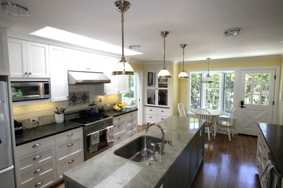Photo of a traditional eat-in kitchen in Charlotte with an undermount sink, recessed-panel cabinets, white cabinets, beige splashback and white appliances.