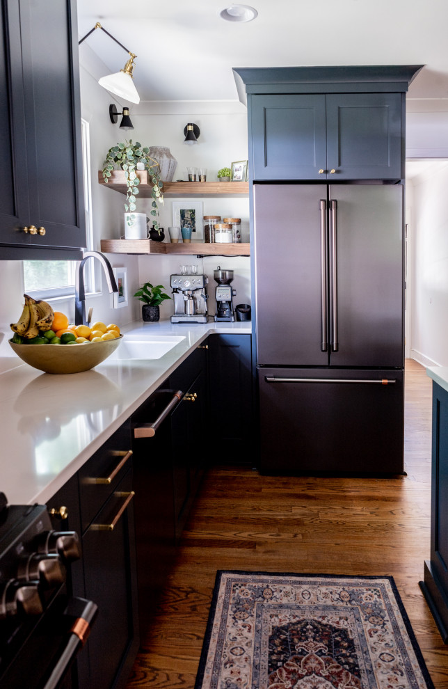 Bild på ett mellanstort funkis vit vitt kök, med en undermonterad diskho, skåp i shakerstil, blå skåp, bänkskiva i kvarts, vitt stänkskydd, svarta vitvaror, mellanmörkt trägolv, en köksö och flerfärgat golv