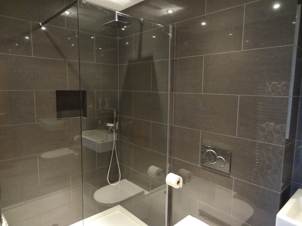 Medium sized modern ensuite bathroom in London with glass-front cabinets, light wood cabinets, a double shower, a one-piece toilet, brown tiles, ceramic tiles, grey walls and ceramic flooring.