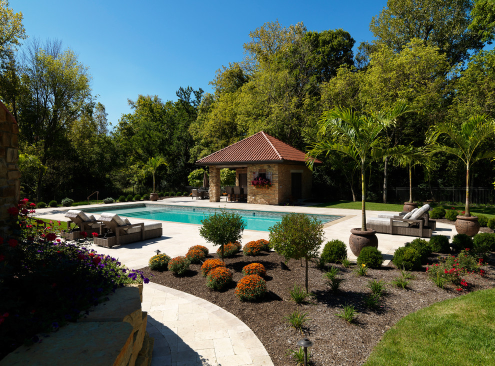 Mid-sized mediterranean backyard rectangular pool in Other with a pool house and natural stone pavers.