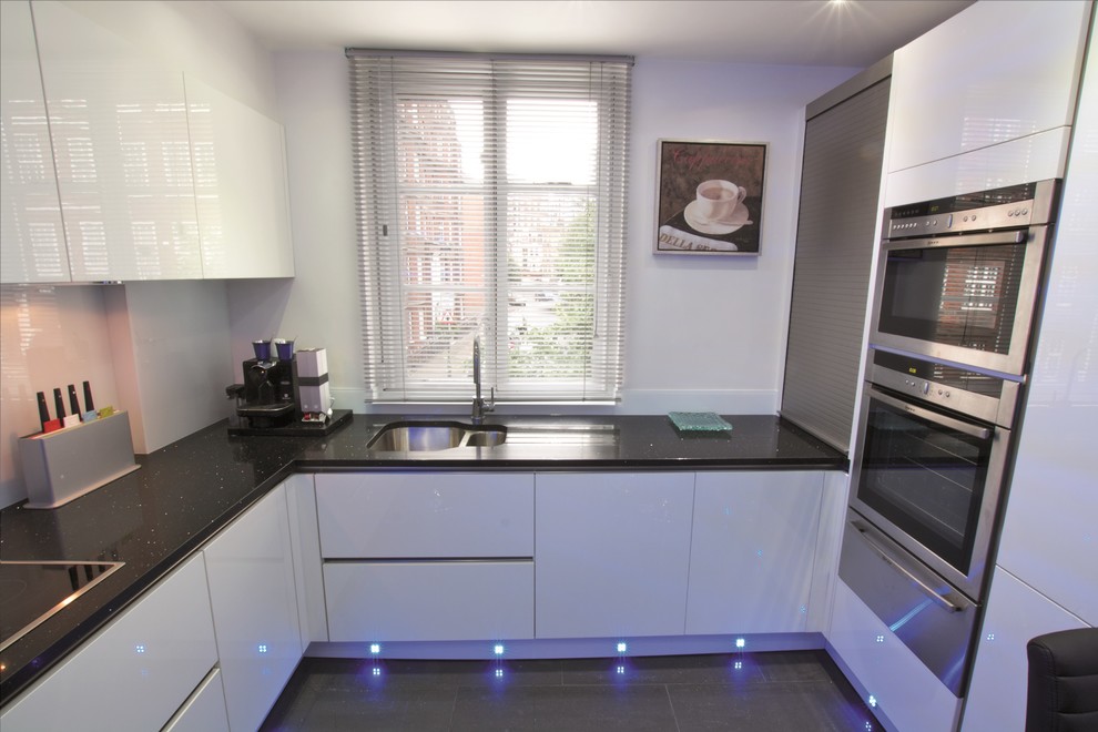 This is an example of a small modern u-shaped kitchen in London with white cabinets.
