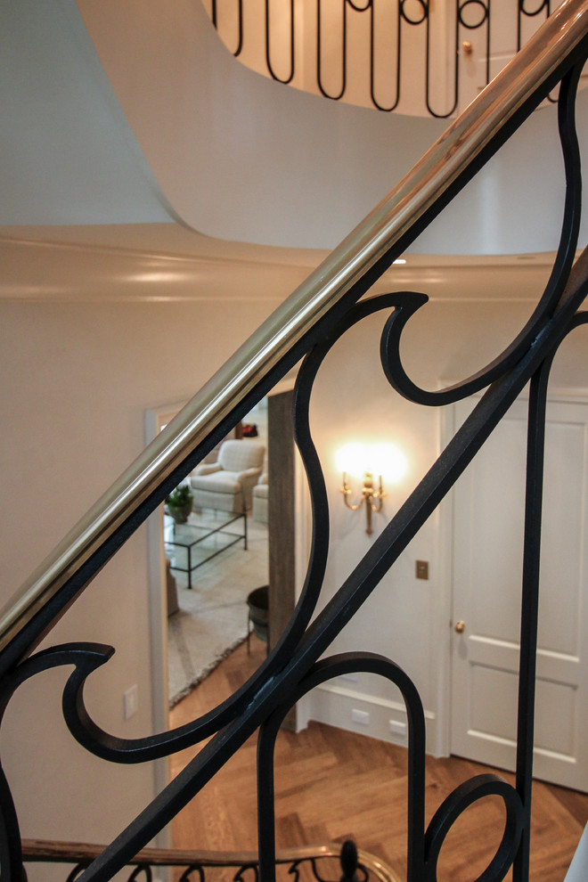 Example of a large transitional wooden curved metal railing staircase design in DC Metro with wooden risers