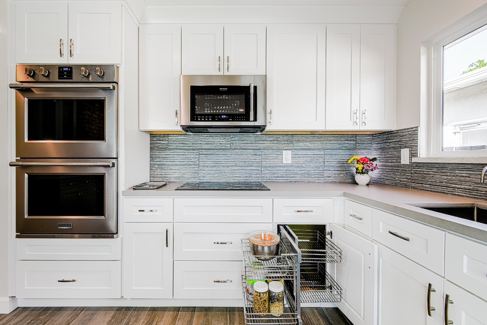 Eat-in kitchen - large transitional l-shaped porcelain tile eat-in kitchen idea in San Francisco with an undermount sink, shaker cabinets, white cabinets, quartz countertops, multicolored backsplash, stone tile backsplash, stainless steel appliances and an island