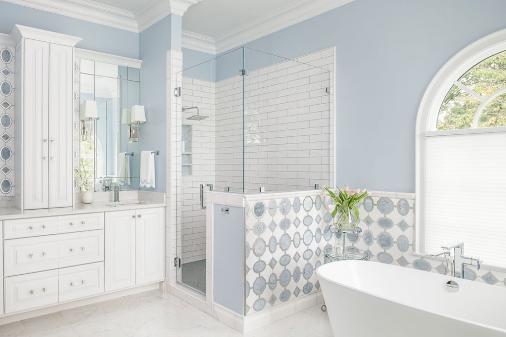 Mid-sized beach style master bathroom in Other with raised-panel cabinets, white cabinets, a freestanding tub, an alcove shower, a two-piece toilet, white tile, ceramic tile, blue walls, ceramic floors, an undermount sink, engineered quartz benchtops, white floor, a hinged shower door, white benchtops, a niche, a double vanity, a built-in vanity, recessed and decorative wall panelling.