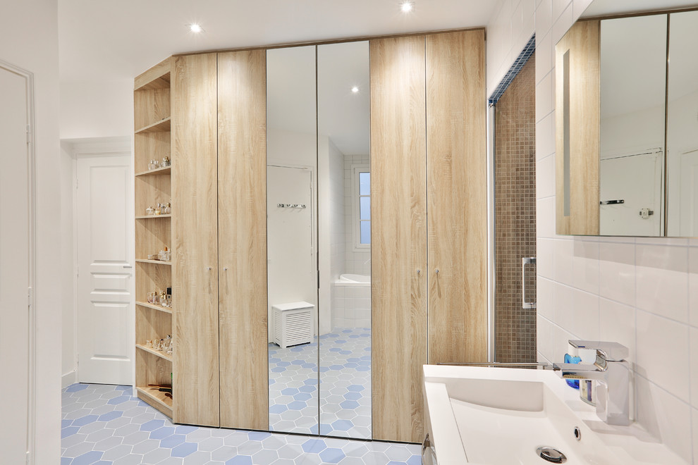 Photo of a large transitional master bathroom in Paris with light wood cabinets, a curbless shower, white tile, white walls, ceramic floors, blue floor, a hinged shower door, beaded inset cabinets, a hot tub, a wall-mount toilet, ceramic tile, a console sink, solid surface benchtops, white benchtops, a shower seat and a double vanity.