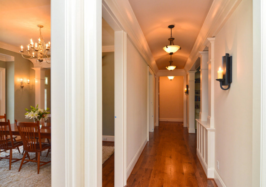 Example of a medium tone wood floor hallway design with white walls
