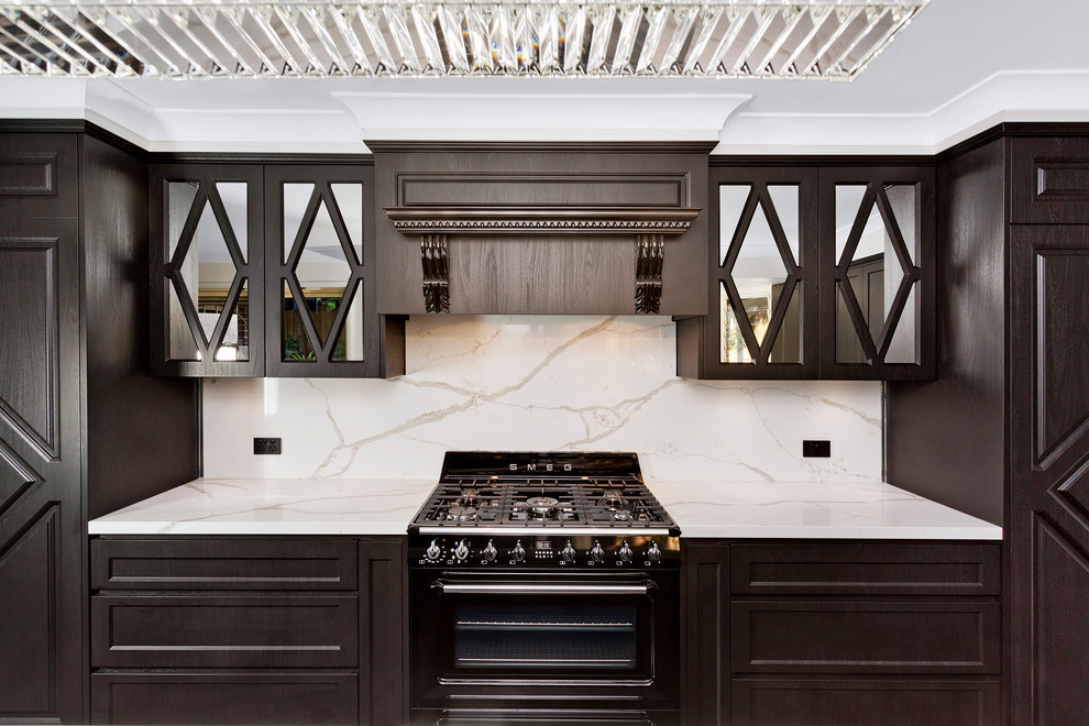 Photo of a midcentury galley open plan kitchen in Central Coast with a single-bowl sink, glass-front cabinets, dark wood cabinets, quartzite benchtops, white splashback, stone slab splashback, black appliances, vinyl floors and with island.