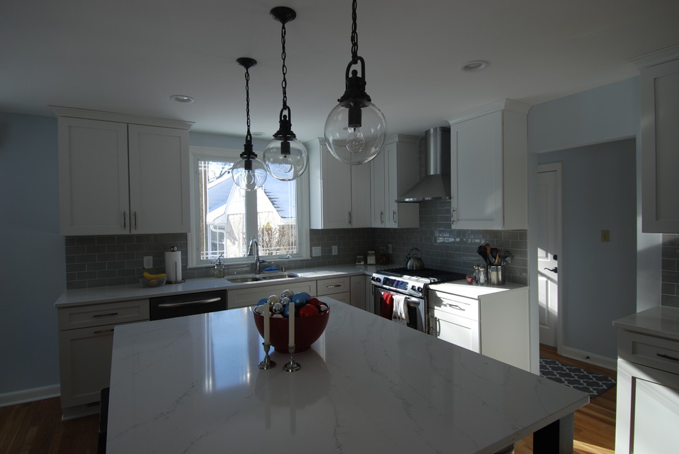 Inspiration for a mid-sized transitional u-shaped medium tone wood floor eat-in kitchen remodel in Milwaukee with an undermount sink, flat-panel cabinets, white cabinets, quartz countertops, gray backsplash, subway tile backsplash, stainless steel appliances, blue walls and an island
