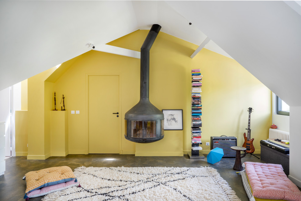 Modern inredning av ett vardagsrum, med ett musikrum, gula väggar, en öppen vedspis, en spiselkrans i metall och grått golv