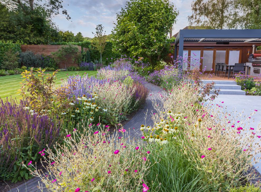 This is an example of a mid-sized contemporary backyard full sun formal garden for summer in Buckinghamshire with with flowerbed and brick pavers.