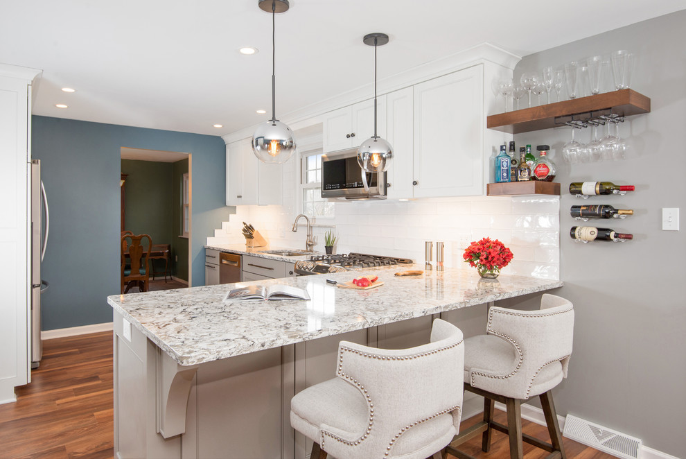 Inspiration for a transitional l-shaped vinyl floor and brown floor enclosed kitchen remodel with an undermount sink, white cabinets, quartz countertops, white backsplash, ceramic backsplash, stainless steel appliances, multicolored countertops, shaker cabinets and a peninsula