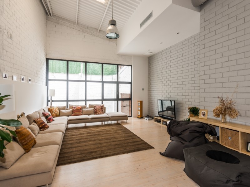 Imagen de sala de estar abierta industrial extra grande sin chimenea con paredes grises, suelo de madera clara y pared multimedia