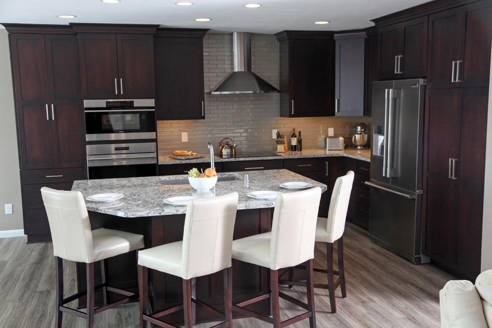 Example of a mid-sized transitional l-shaped vinyl floor open concept kitchen design in Milwaukee with an undermount sink, flat-panel cabinets, dark wood cabinets, quartz countertops, gray backsplash, glass tile backsplash, stainless steel appliances and an island