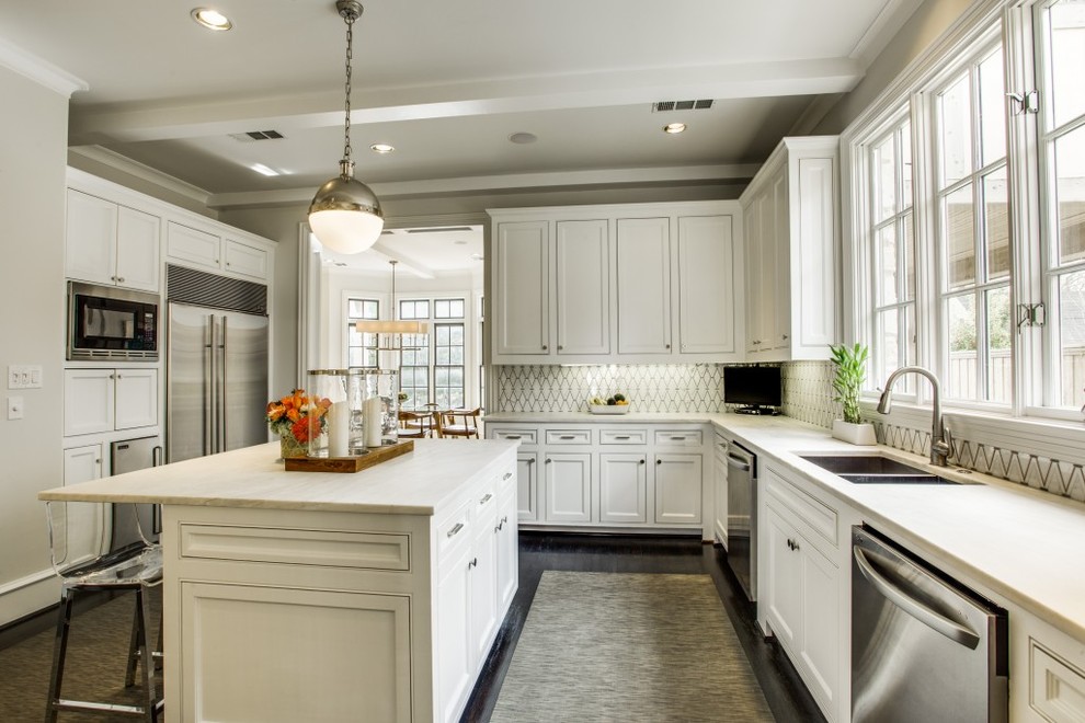 Design ideas for a mid-sized traditional u-shaped kitchen in Dallas with white cabinets, white splashback, stone tile splashback, stainless steel appliances, dark hardwood floors, with island, an undermount sink and beaded inset cabinets.