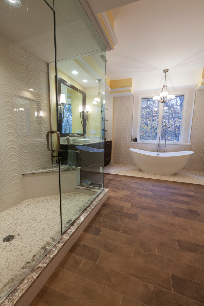 Large contemporary master bathroom in New York with flat-panel cabinets, brown cabinets, a freestanding tub, a corner shower, a two-piece toilet, white tile, porcelain tile, yellow walls, pebble tile floors, a vessel sink, quartzite benchtops, beige floor and a hinged shower door.