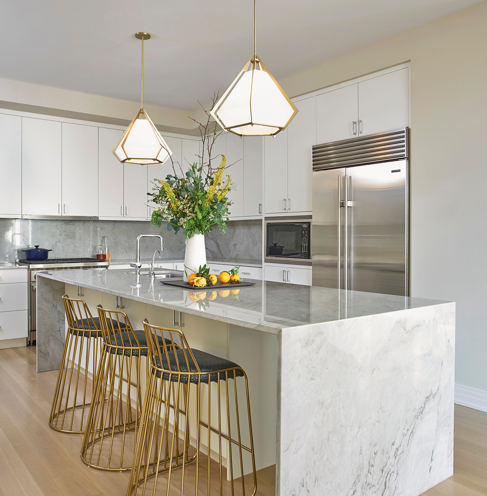 Design ideas for a contemporary l-shaped kitchen in Chicago with an undermount sink, flat-panel cabinets, white cabinets, grey splashback, stone slab splashback, stainless steel appliances, medium hardwood floors, with island and brown floor.