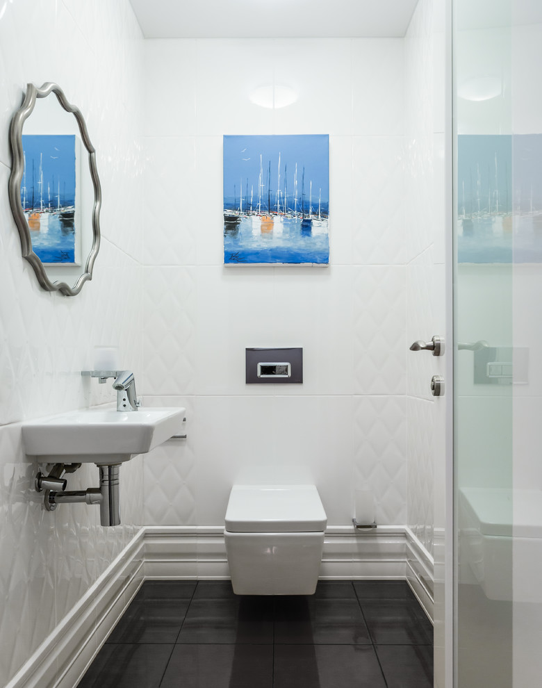 Photo of a transitional powder room in Moscow with a wall-mount toilet, white tile, a wall-mount sink and black floor.