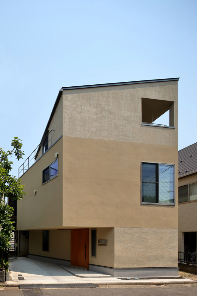 Cette image montre une petite façade de maison beige en stuc à deux étages et plus avec un toit en appentis, un toit en métal et un toit gris.
