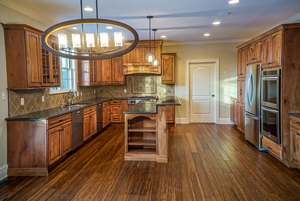 Mid-sized mountain style u-shaped medium tone wood floor eat-in kitchen photo in Chicago with an undermount sink, raised-panel cabinets, distressed cabinets, granite countertops, beige backsplash, stone tile backsplash, stainless steel appliances and an island
