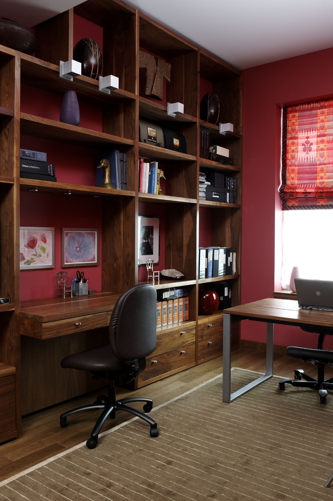 Contemporary home office in New York with a built-in desk and red walls.